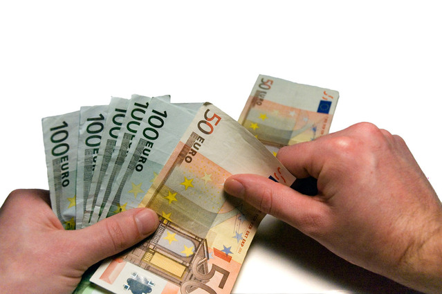 člověk počítající eurobankovky na stole